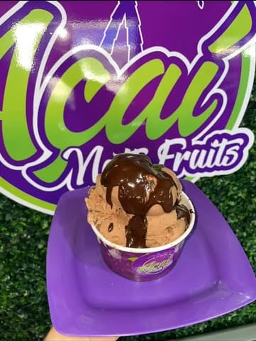 Bola de sorvete de chocolate com calda escorrendo, num prato roxo